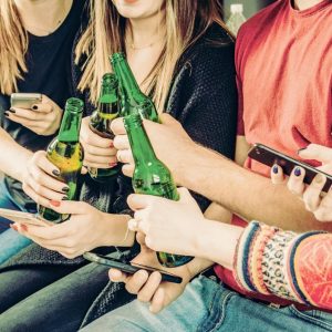 Young friends drink alcohol and use smartphones - Millennials party after skiing - Friends raise a toast for a good day and send messages on social networks.